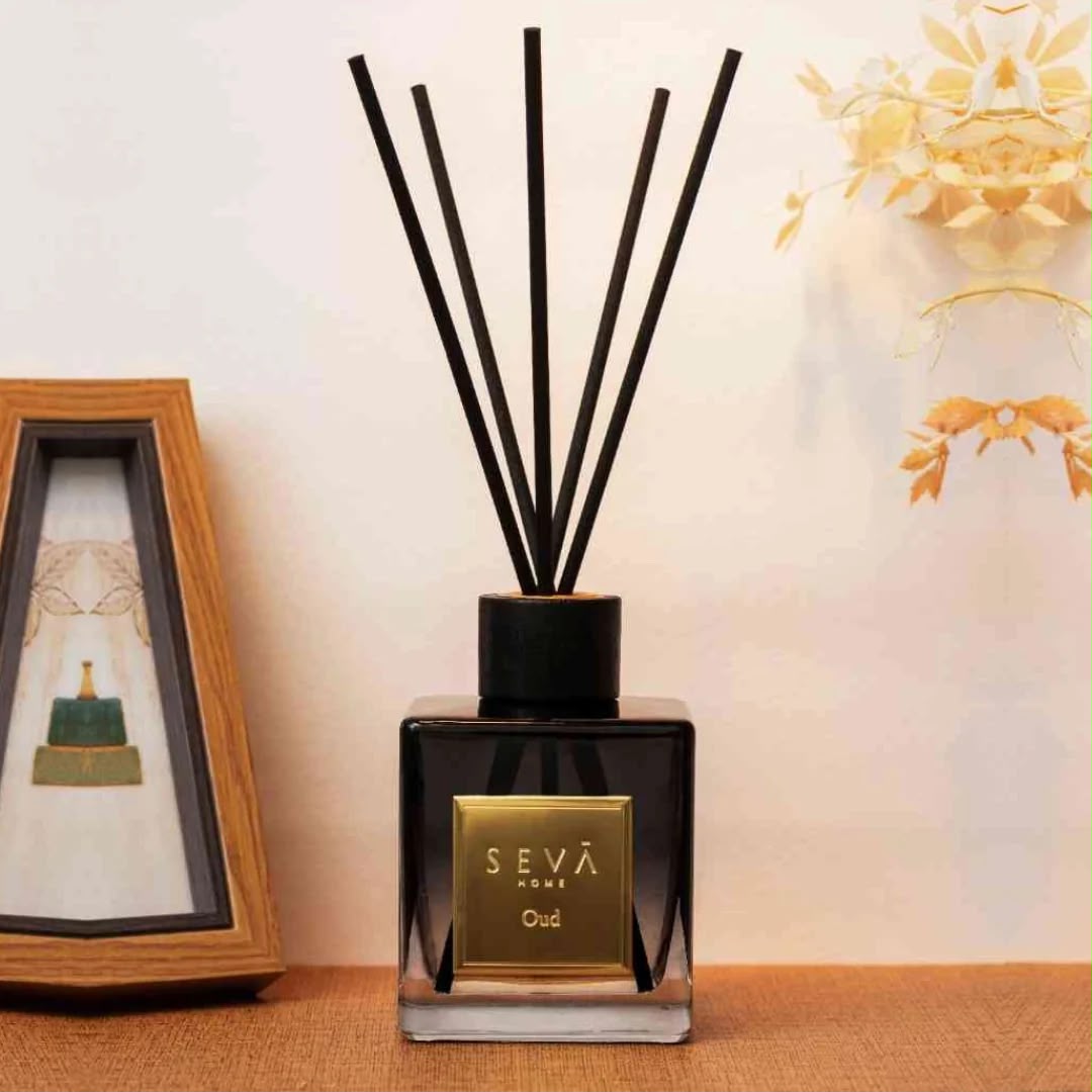 Black glass reed diffuser with tall black reeds on a linen surface
